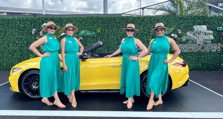 Four women in green dresses standing in front of yellow vehicle