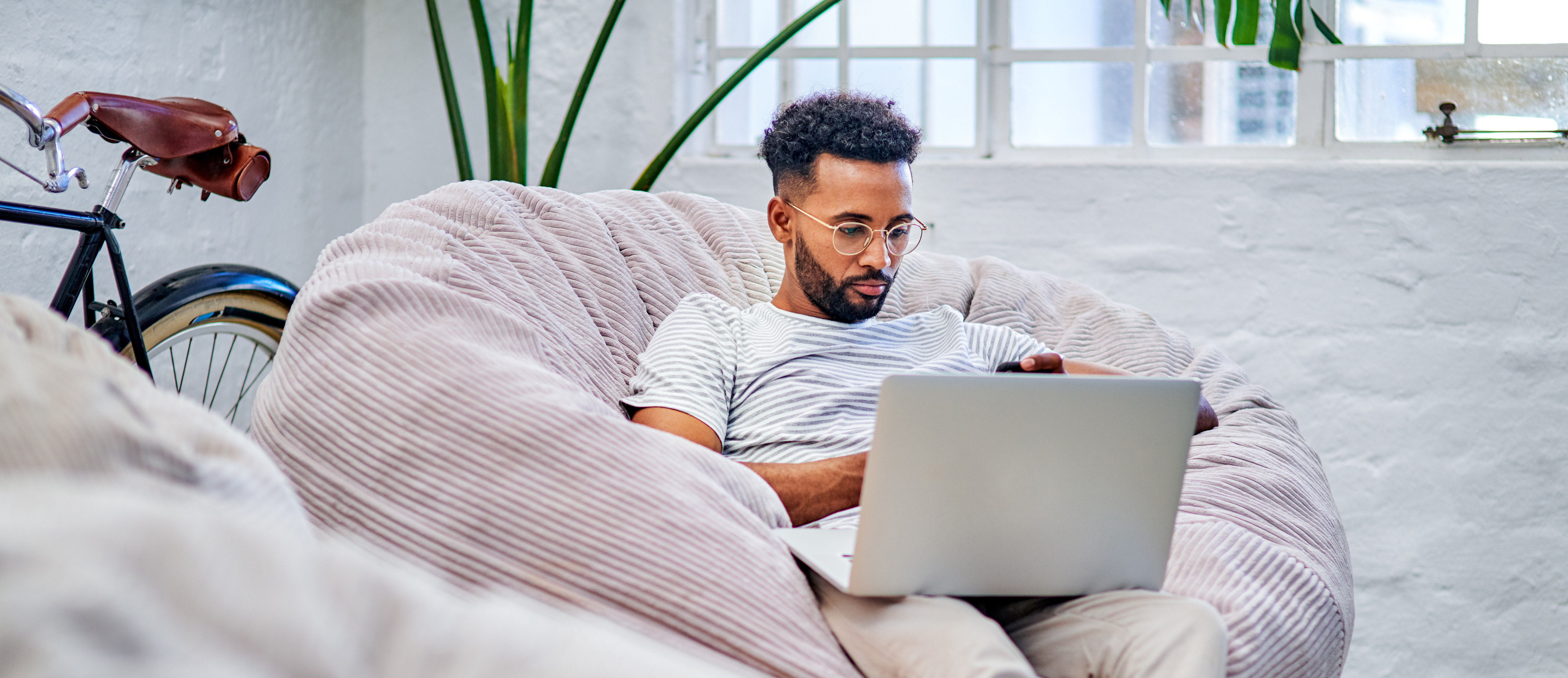 Image of man sitting on a couch looking at his laptop to update his talent profile.